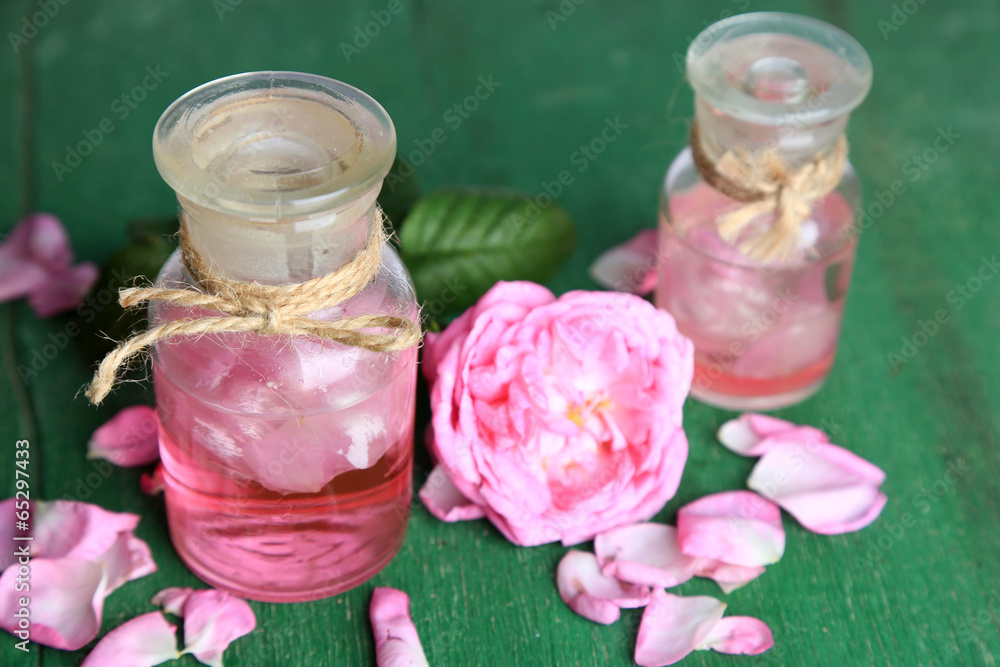 Rose oil in bottles on color wooden background Rose oil in bottles on color wooden background