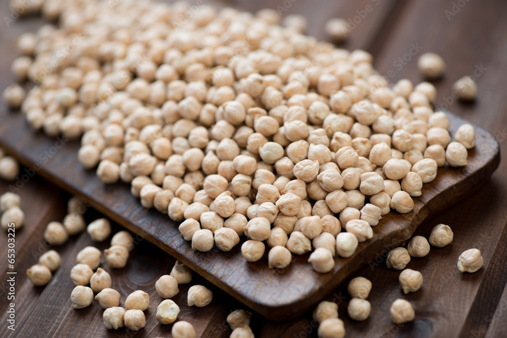 Raw chickpeas on a rustic wooden chopping board, studio shot Raw chickpeas on a rustic wooden chopping board, studio shot