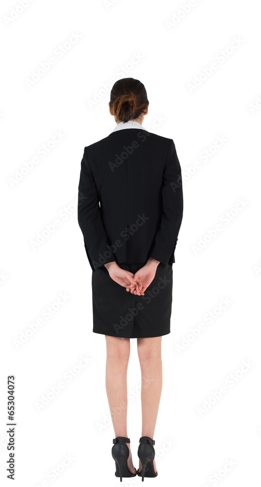 Businesswoman in suit standing with hands behind back Businesswoman in suit standing with hands behind back