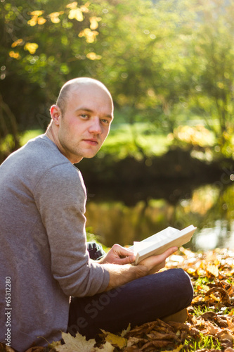 Young man relaxing in a park, reading a book