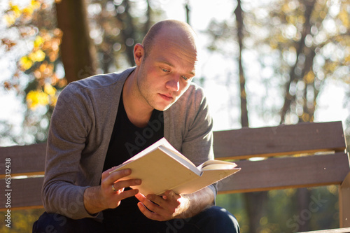 Young man relaxing in a park, reading a book
