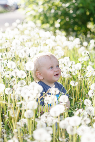 little baby boy sitting on a green meadow