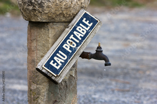 Vintage faucet of drinking water source, with sign in French