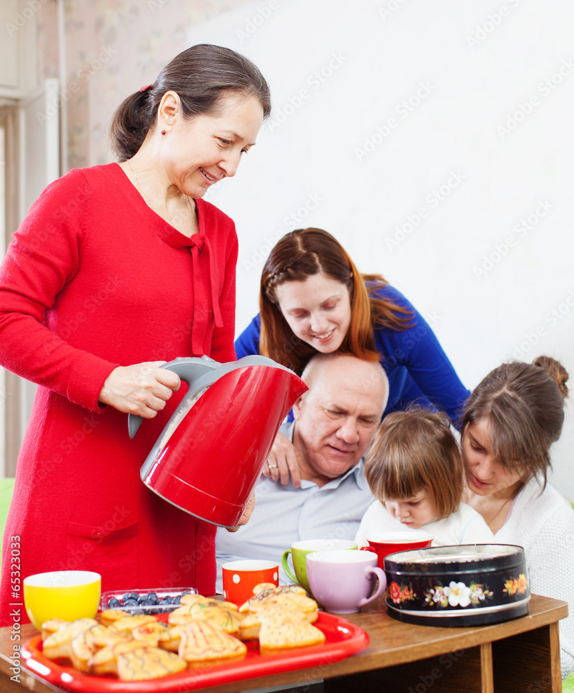 Mature woman pours tea for her family
