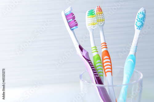 Toothbrushes in glass on table on light background