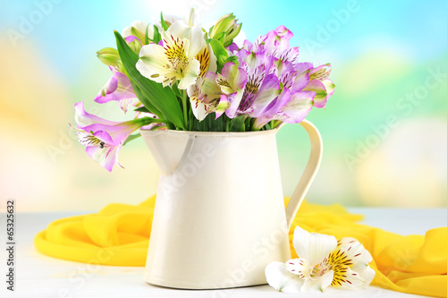 Bouquet of freesias in pitcher on table on natural background