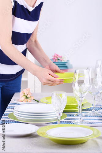Woman laying table in room