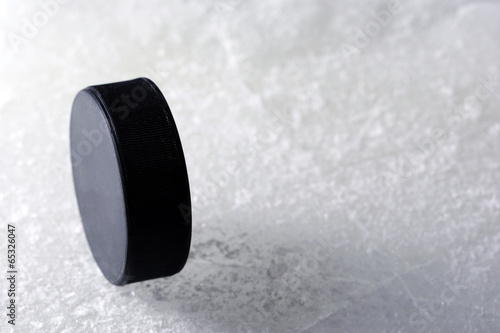 Canvas Print Black hockey puck on ice rink background