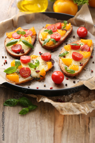 Tasty bruschetta with tomatoes on pan, on old wooden table