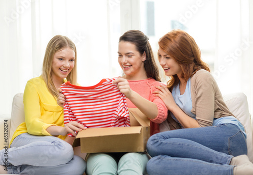 smiling teenage girls opening cardboard box