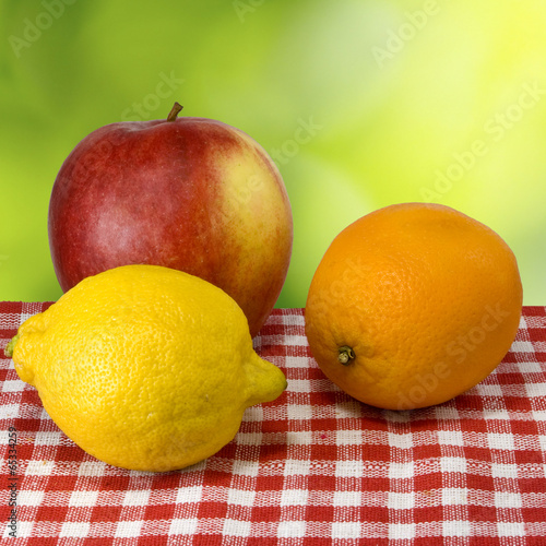 image of an apple, lemon and orange on green background