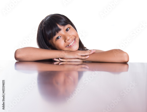 Young Asian Malay girl with face reflection on a table surface