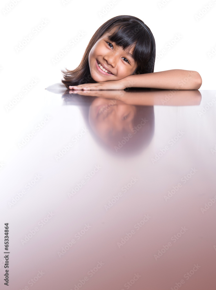 Young Asian Malay girl with face reflection on a table surface Young Asian Malay girl with face reflection on a table surface