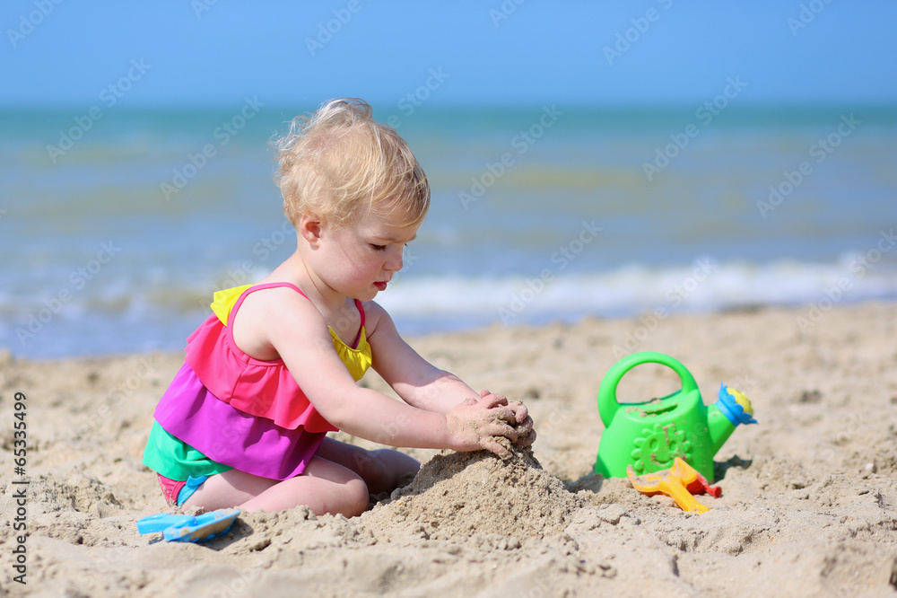 Cute little girl building sand castles on tropical beach Cute little girl building sand castles on tropical beach