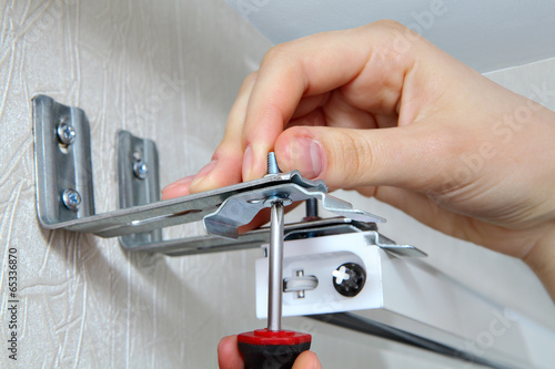 Canvas Print vertical blinds mounting brackets, hand with a screw close up