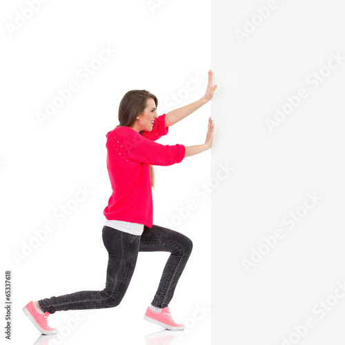 Young woman pushing the wall photo