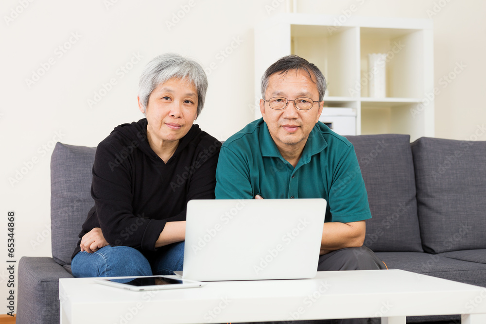 Elder couple staying at home with laptop computer