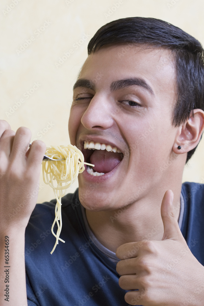 Young man eating spaghetti - thumbs up. Young man eating spaghetti - thumbs up.