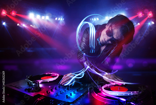 Disc jockey playing music with light beam effects on stage photo