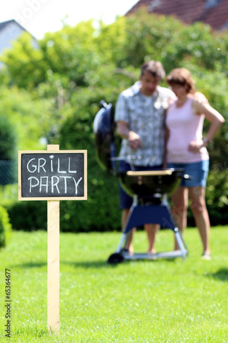 Mann grillt mit Frau Schild: "Grillparty" im Garten