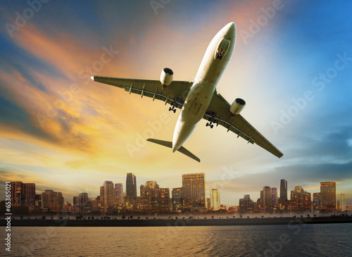 Canvas Print passenger plane flying above urban scene use for convenience air