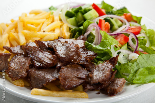 Grilled meat with French fries and vegetables