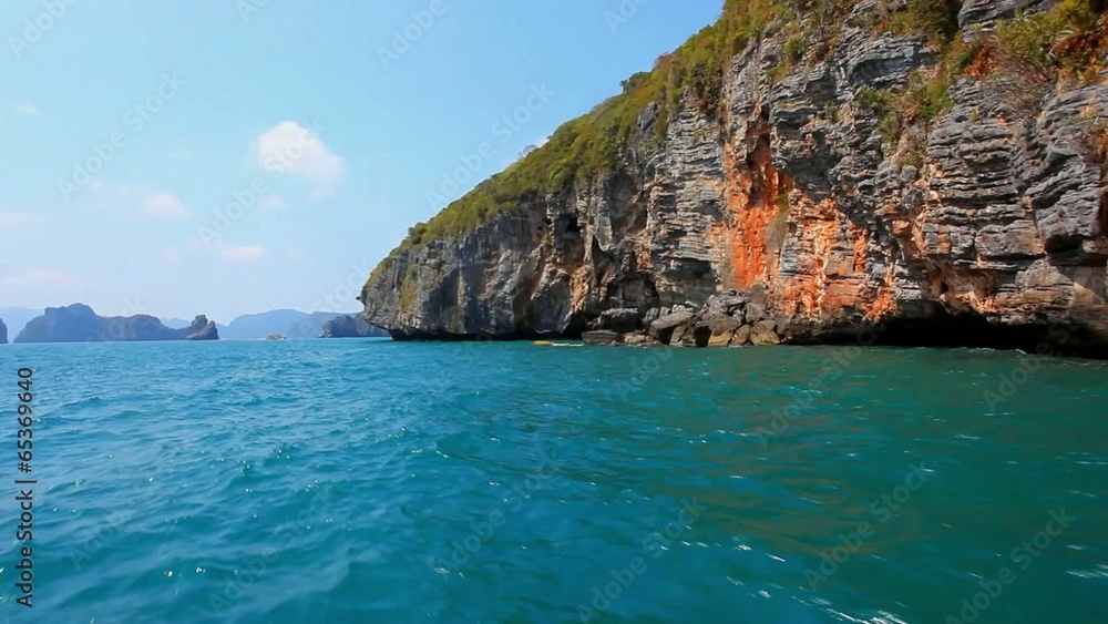 Sailing of speed boat next to a rock islands in accelerated time Sailing of speed boat next to a rock islands in accelerated time