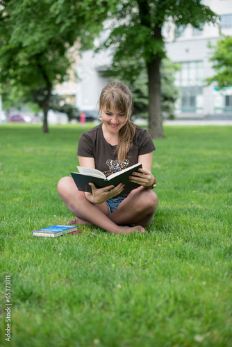beautiful girl reads book in a park