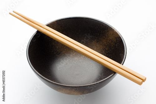 Chopsticks and black bowl isolated on white