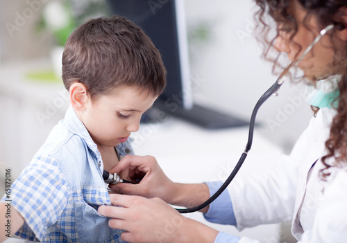 Young friendly female doctor examining a little boy photo