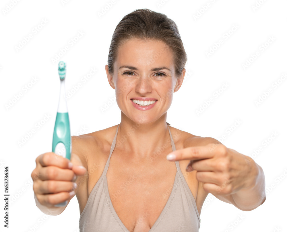 Portrait of smiling young woman pointing on toothbrush Portrait of smiling young woman pointing on toothbrush