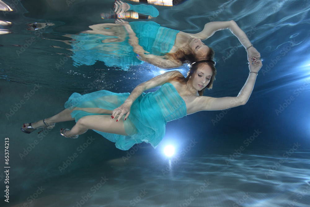 Woman with dress posing underwater in the pool
