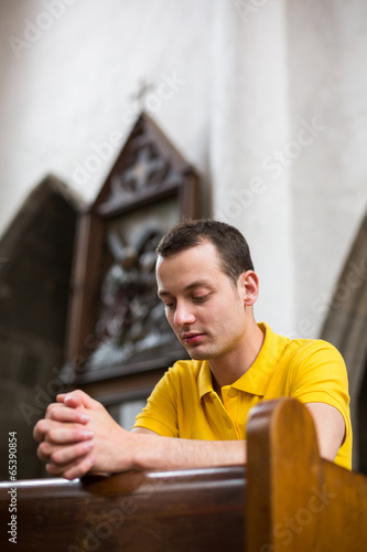Photos Handsome young man praying in a church