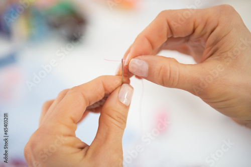 Closeup on seamstress threading needle