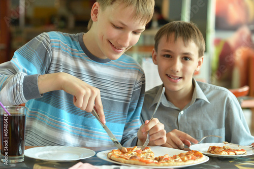 Two boys eatning pizza