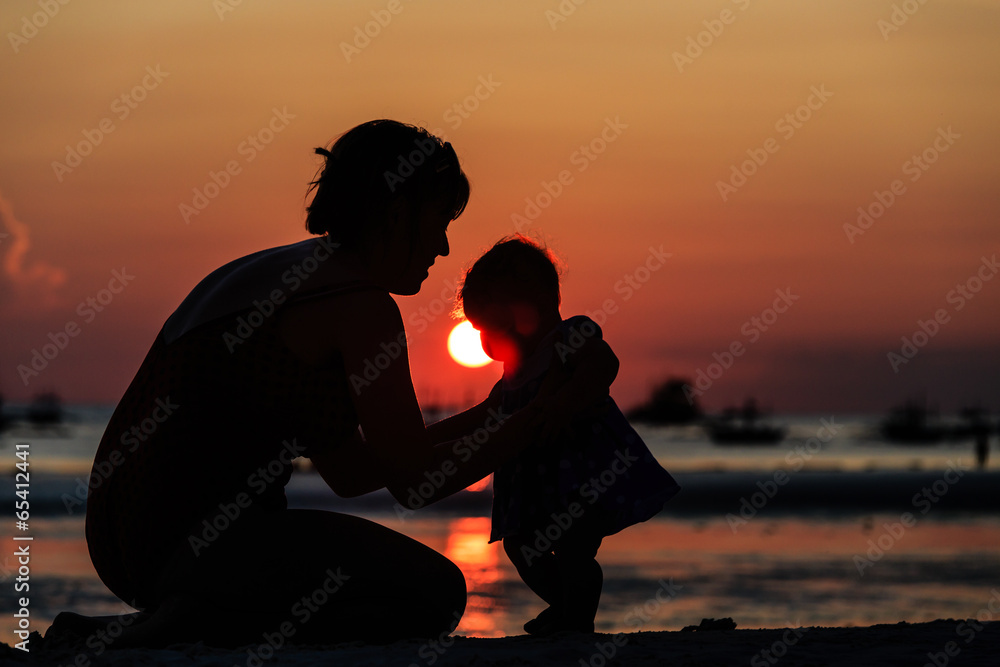 Silhouette of mother and daughter on sunset beach