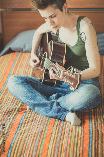 young lesbian stylish hair style woman playing guitar