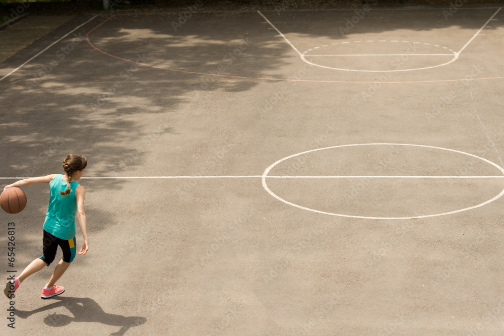 Energetic teenage girl playing basketball