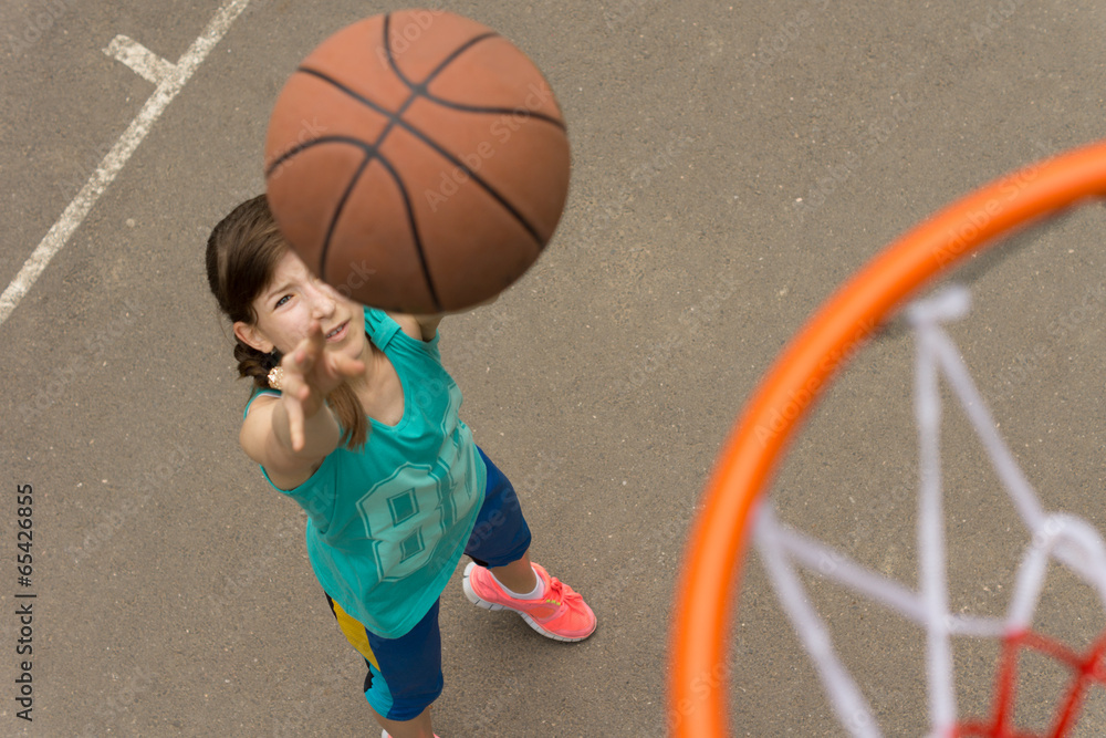 Teenage girl shooting for a goal in basketball