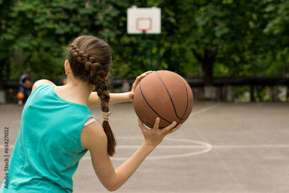 Young slender teenage girl playing basketball