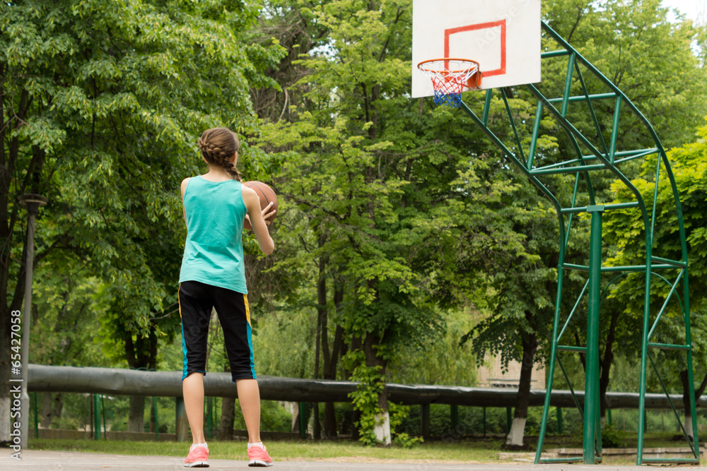 Athletic slender young girl playing basketball