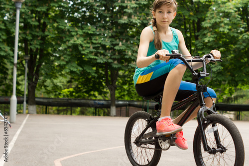 Teenage girl riding a borrowed kids bike