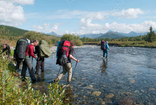 hikers crossing mountain river, Ural, Russia