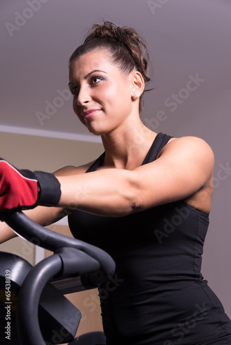 Woman smiling on exercise bicycle in the fitness room.