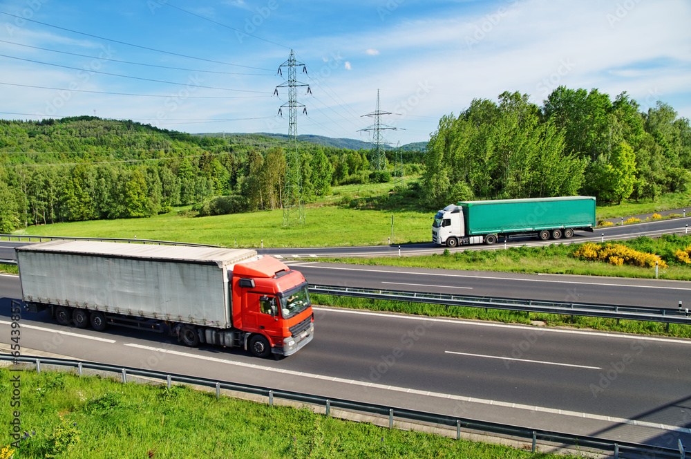 A country landscape with highway, two trucks