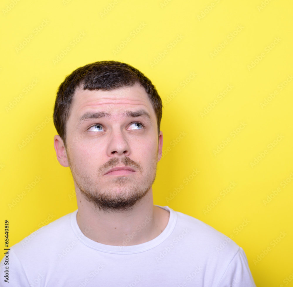 Portrait of happy young man looking up against yellow background Portrait of happy young man looking up against yellow background