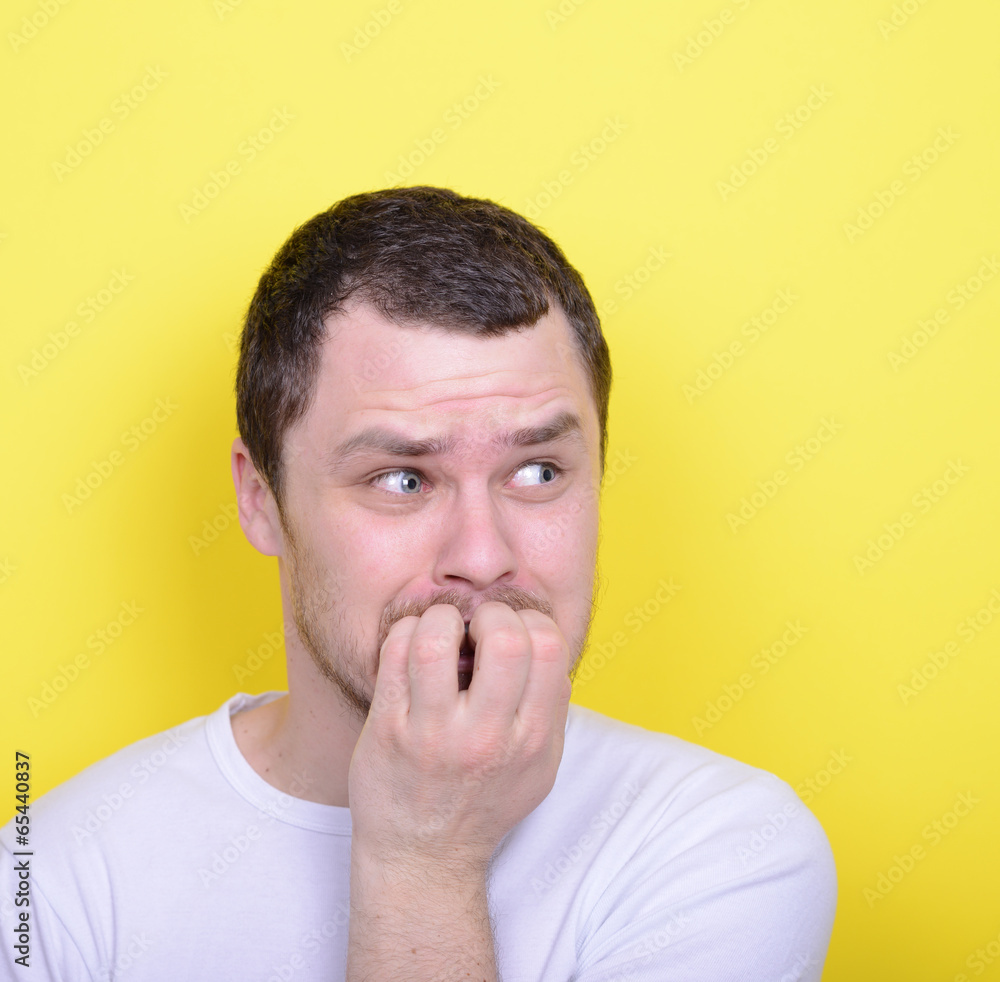 Portrait of man biting nails against yellow background