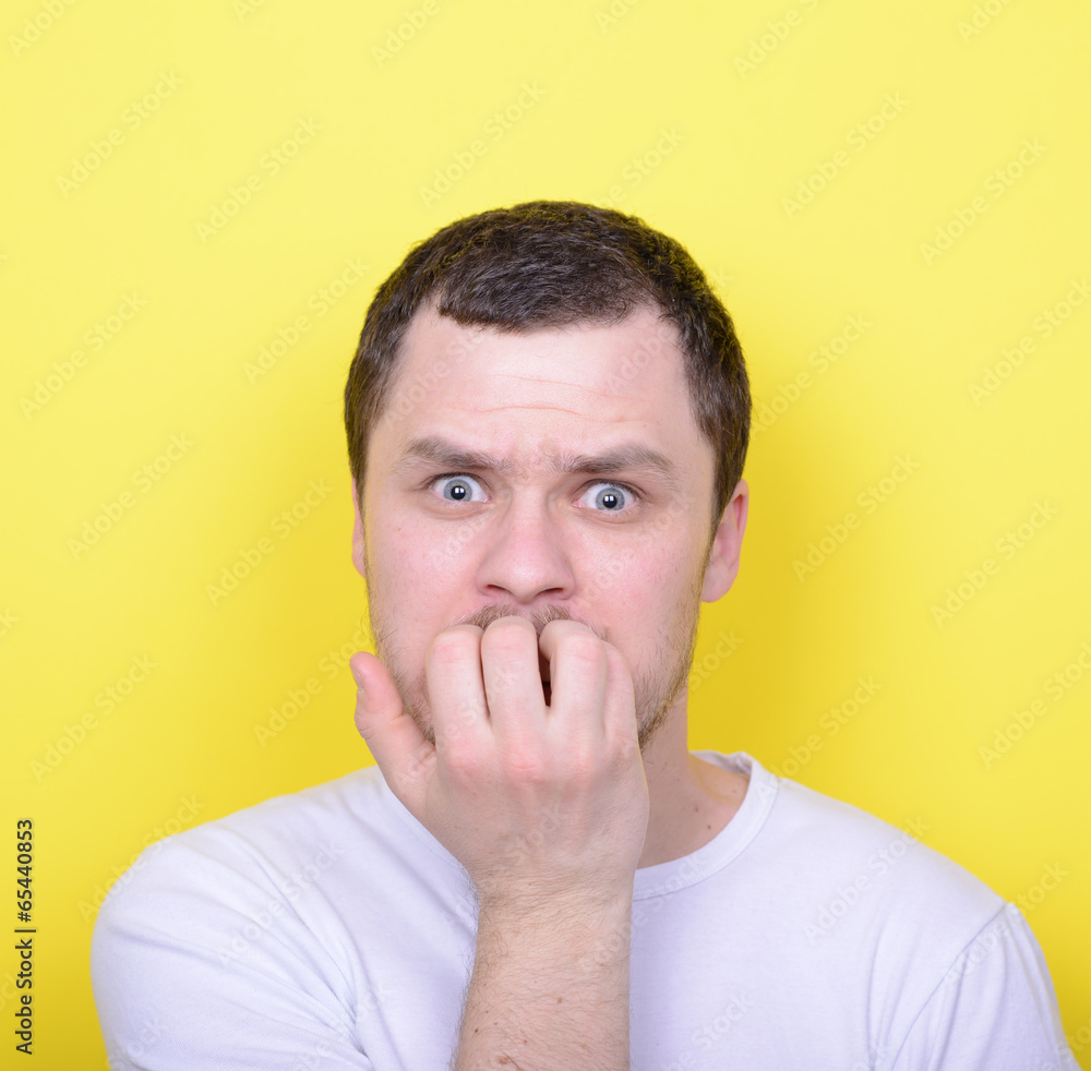 Portrait of man biting nails against yellow background Portrait of man biting nails against yellow background