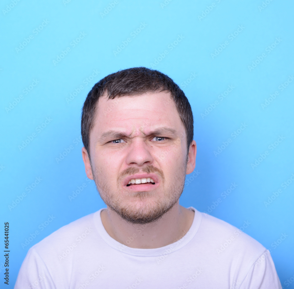 Portrait of man with dusgusted gesture against blue background Portrait of man with dusgusted gesture against blue background