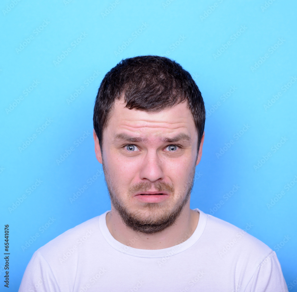 Portrait of man with dusgusted gesture against blue background Portrait of man with dusgusted gesture against blue background